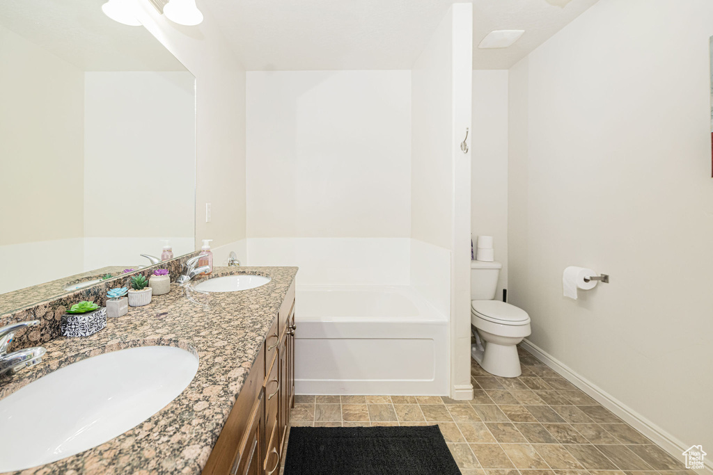Full bathroom with a tub, baseboards, a sink, and toilet