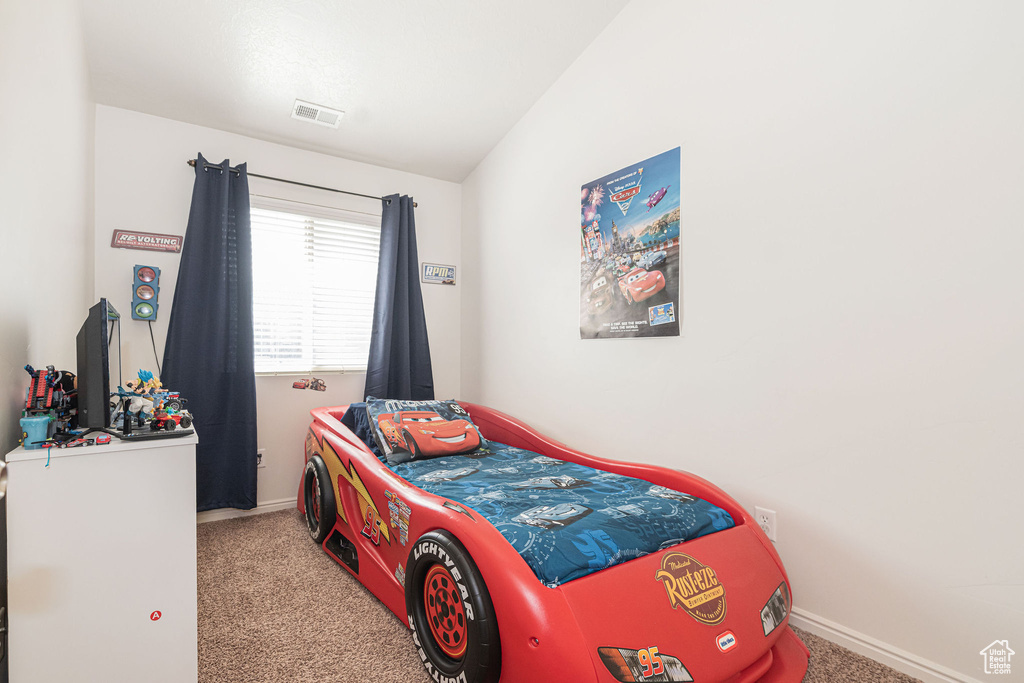 Carpeted bedroom with baseboards, visible vents, and vaulted ceiling