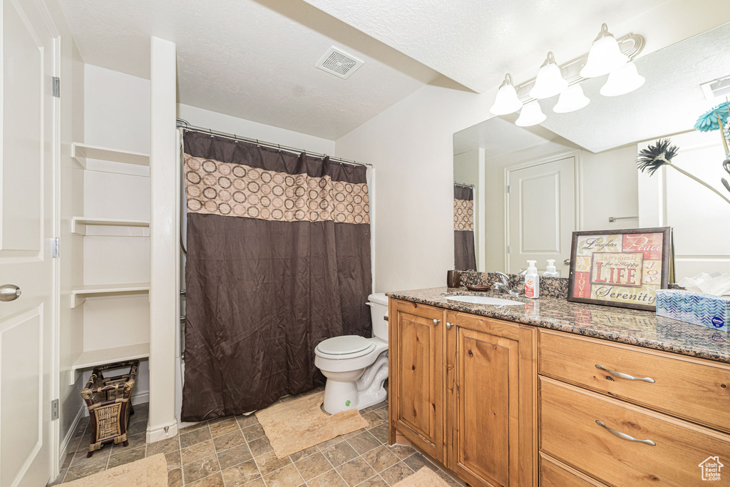 Full bathroom featuring stone finish floor, visible vents, vanity, and toilet