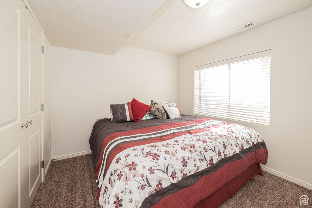 Bedroom with carpet floors, baseboards, visible vents, and a textured ceiling