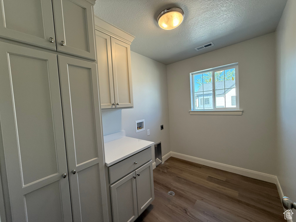 Washroom featuring electric dryer hookup, cabinet space, a textured ceiling, baseboards, and washer hookup