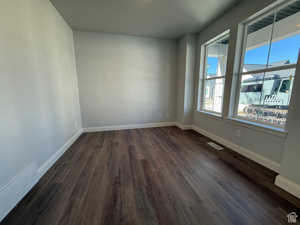 Spare room featuring dark wood-type flooring and baseboards