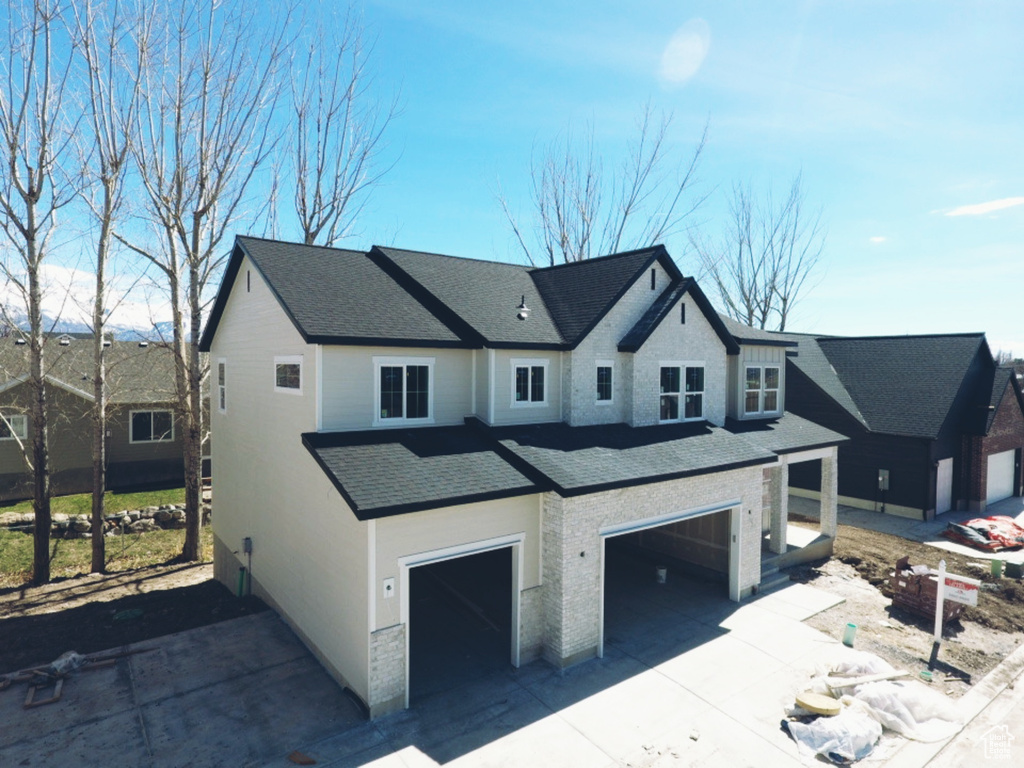 View of front of property with an attached garage, a shingled roof, and concrete driveway