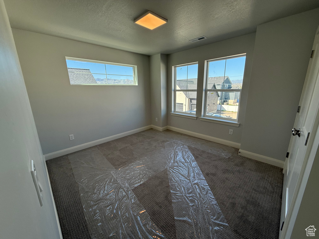 Unfurnished bedroom with carpet flooring, baseboards, and a textured ceiling