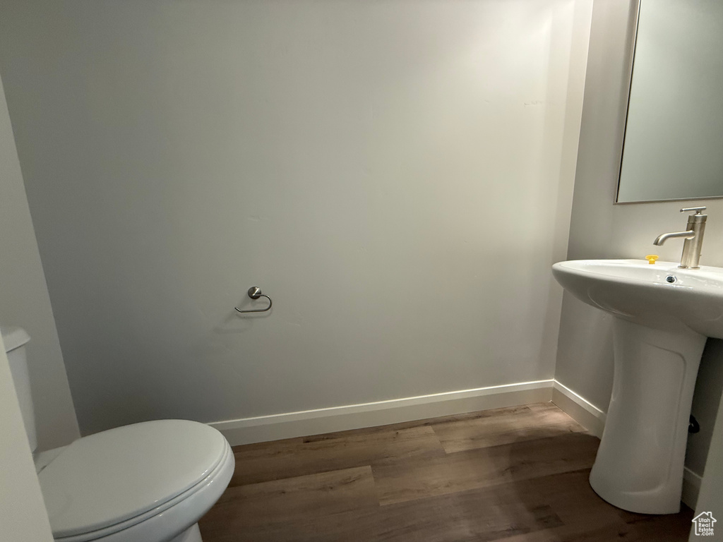 Bathroom featuring wood finished floors, baseboards, toilet, and a sink