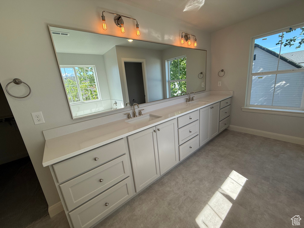 Bathroom with plenty of natural light, double vanity, and baseboards