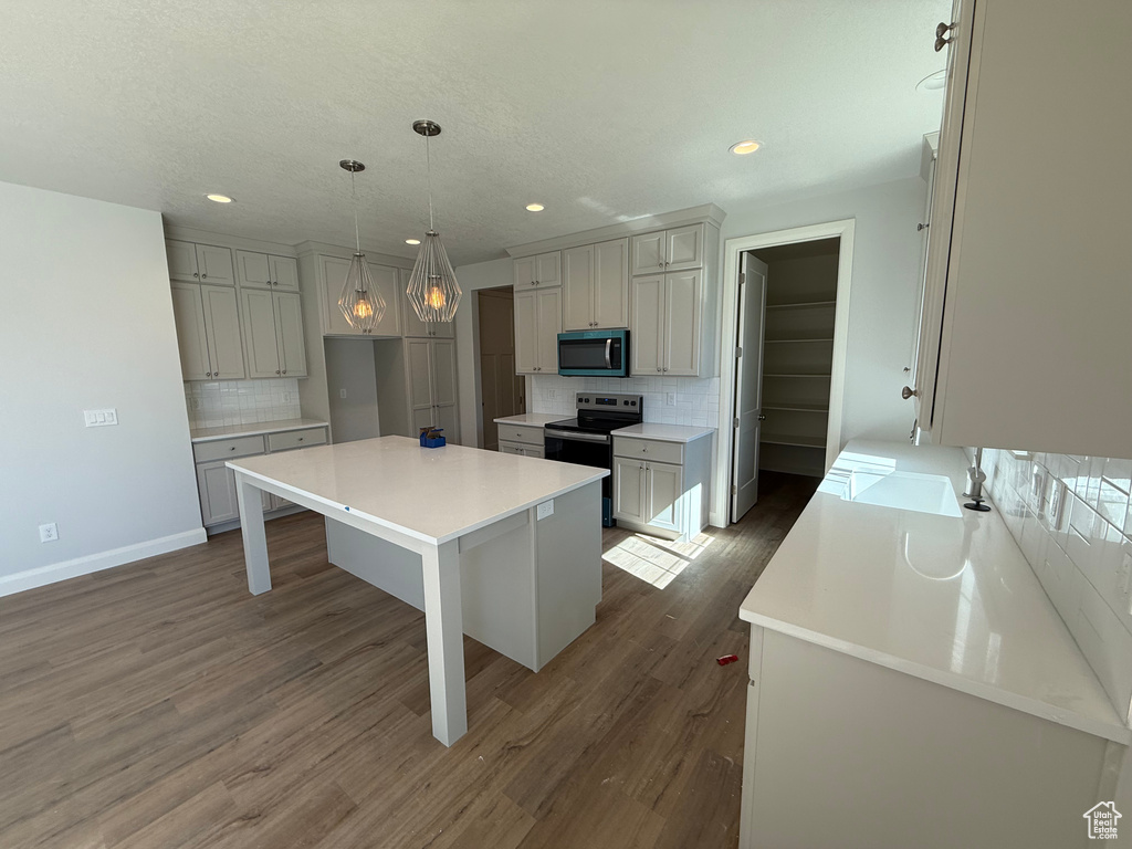 Kitchen with stainless steel range with electric stovetop, decorative backsplash, dark wood-style flooring, recessed lighting, and a kitchen island