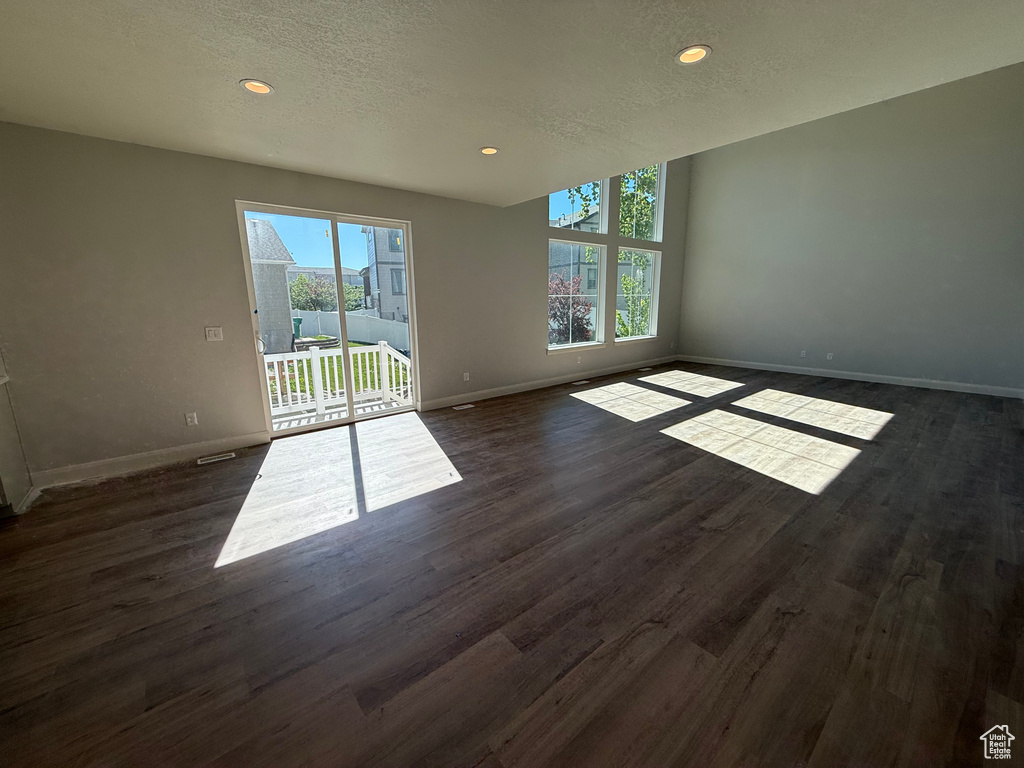 Spare room with baseboards, dark wood-style flooring, recessed lighting, and a textured ceiling