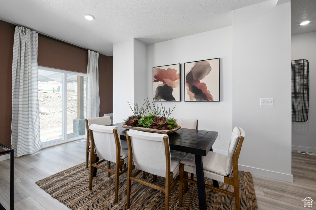 Dining area featuring light wood-type flooring, a textured ceiling, baseboards, and recessed lighting