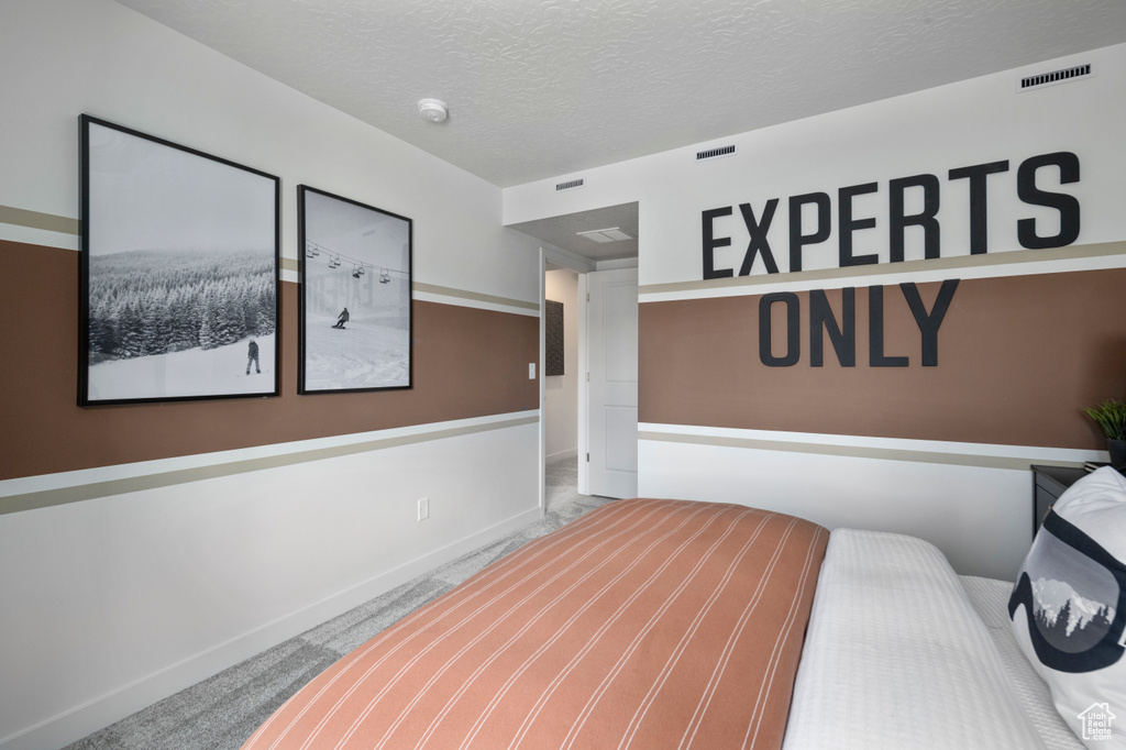 Carpeted bedroom featuring baseboards and a textured ceiling
