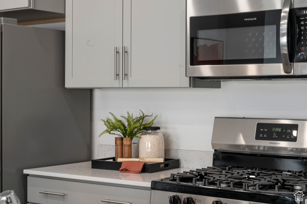 Kitchen featuring appliances with stainless steel finishes, white cabinets, and light stone counters