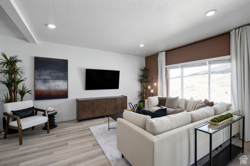 Living area with light wood-style flooring, baseboards, a textured ceiling, and recessed lighting