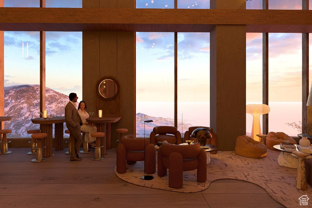 Interior space featuring a healthy amount of sunlight, a mountain view, a wall of windows, and wood finished floors