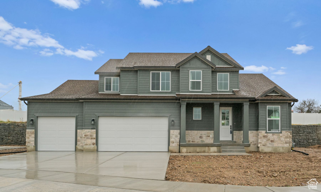 View of front of property featuring concrete driveway, an attached garage, stone siding, and a shingled roof