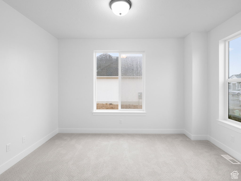 Spare room featuring light colored carpet, baseboards, and visible vents