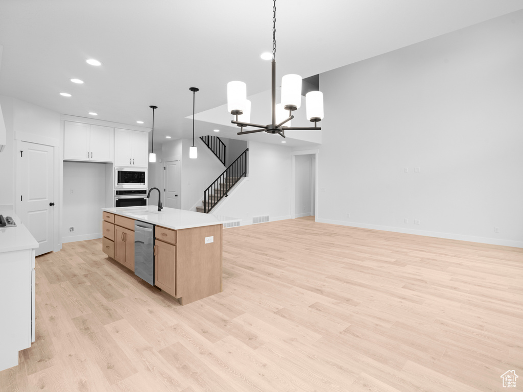 Kitchen featuring stainless steel appliances, light wood-style flooring, open floor plan, recessed lighting, and light countertops