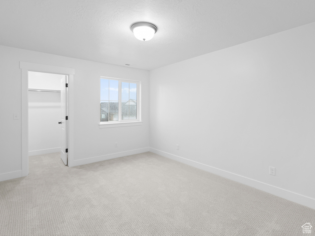 Spare room with light colored carpet, baseboards, and a textured ceiling
