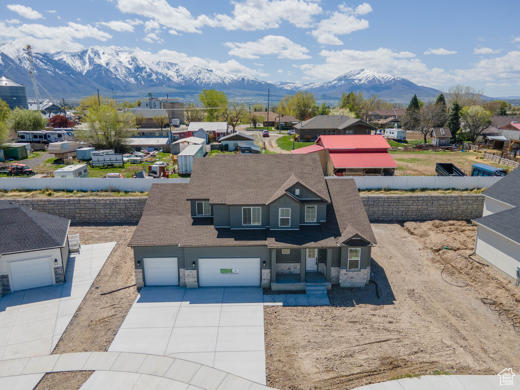 View of front of home with a residential view, concrete driveway, an attached garage, a porch, and a mountain view