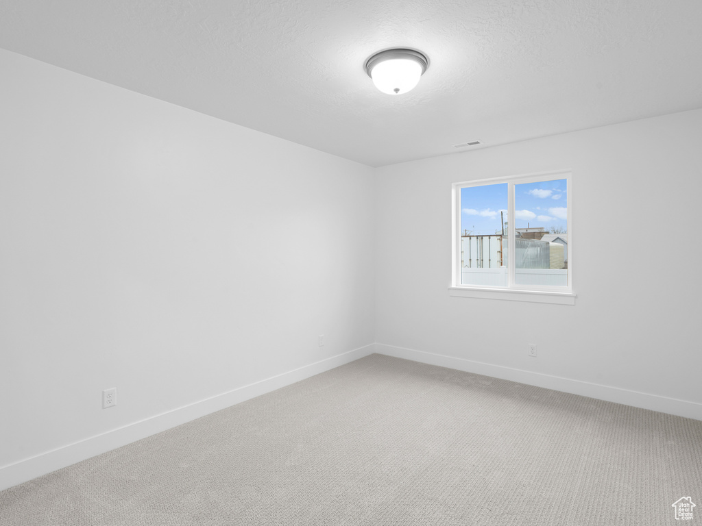 Empty room with visible vents, light carpet, and baseboards