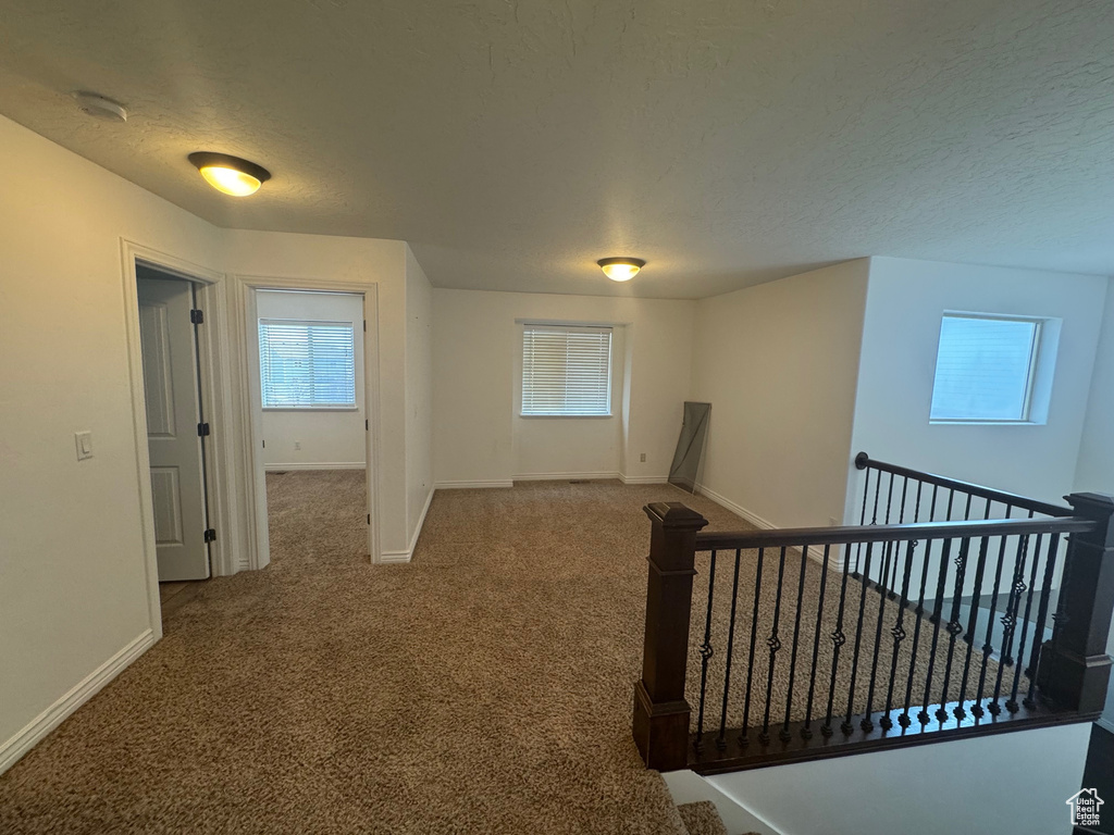 Corridor with carpet floors, baseboards, and an upstairs landing