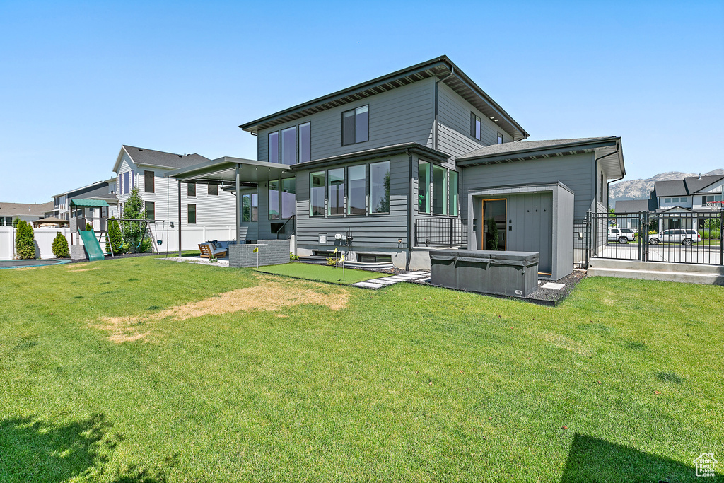 Back of property with a hot tub, a fenced backyard, and a patio area