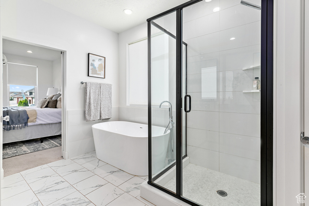 Bathroom featuring a soaking tub, marble look tiles, a shower stall, ensuite bathroom, and recessed lighting