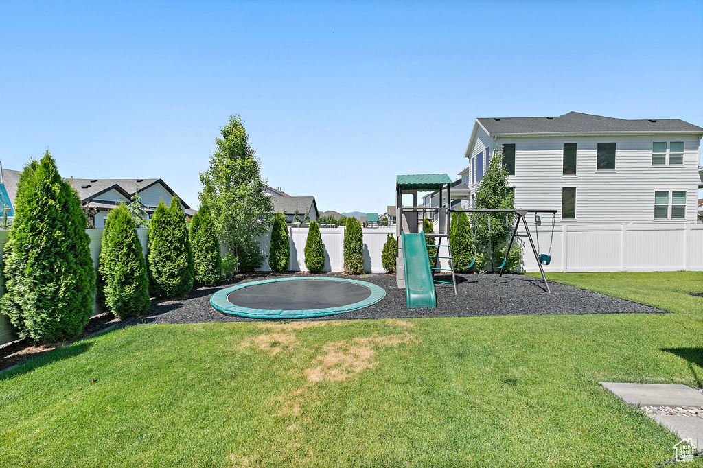 Fenced backyard featuring a trampoline and a residential view