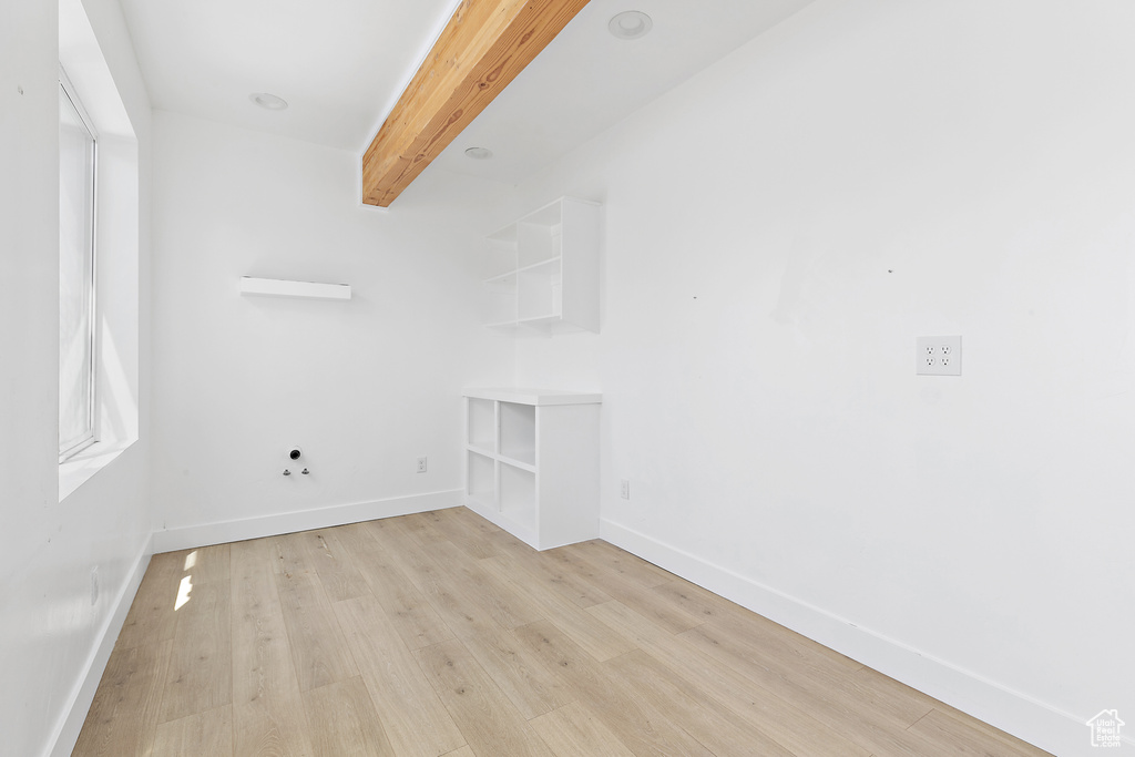 Spare room with light wood-style flooring and beamed ceiling