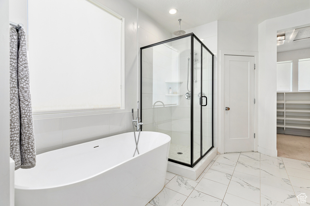 Full bathroom with a stall shower, a freestanding tub, marble look tile flooring, and recessed lighting