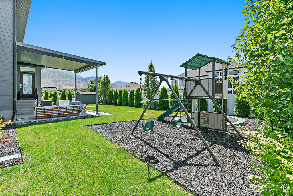 Community play area featuring a fenced backyard, a mountain view, and an outbuilding