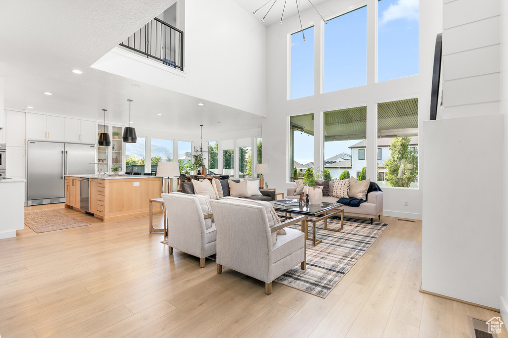 Living room with light wood-style floors, a high ceiling, and recessed lighting