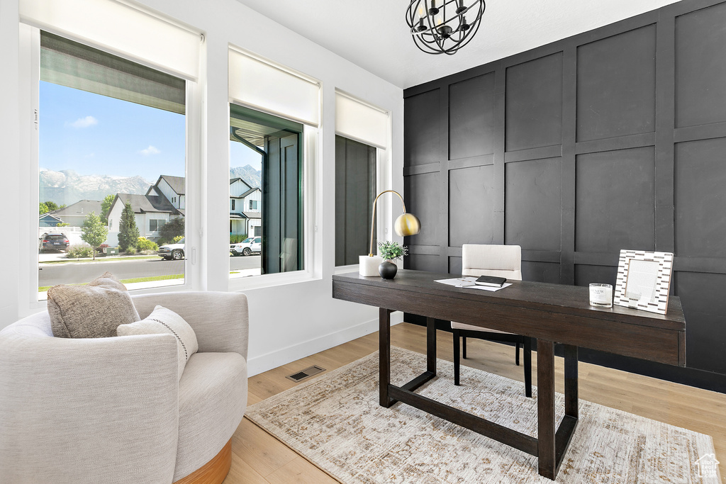 Office space featuring a decorative wall, a chandelier, and light wood finished floors