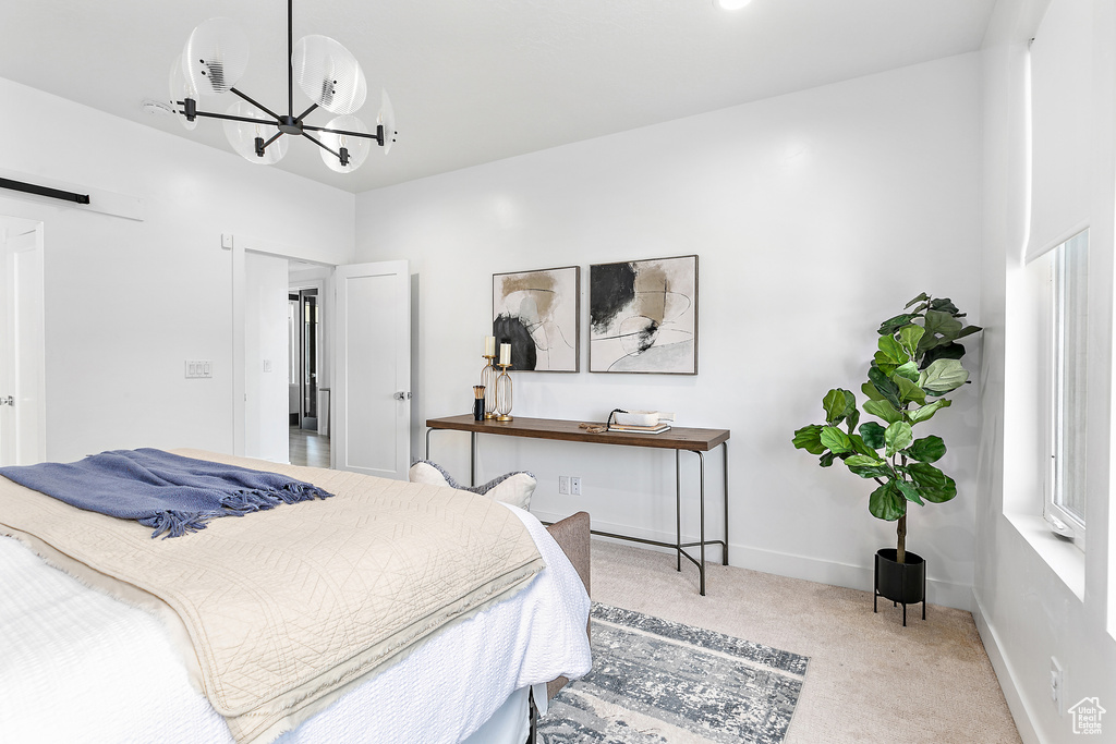 Carpeted bedroom featuring a chandelier and a barn door