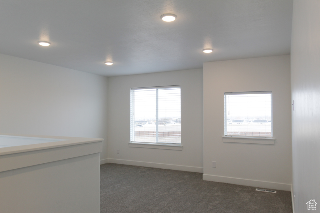 Spare room featuring recessed lighting, dark carpet, visible vents, and baseboards