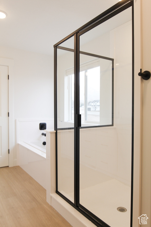 Bathroom featuring a bath, wood finished floors, and a stall shower