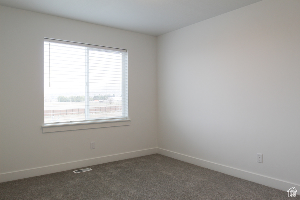 Empty room featuring baseboards, carpet flooring, visible vents, and plenty of natural light