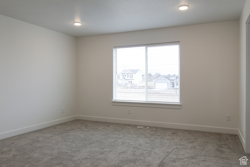 Carpeted spare room with baseboards and visible vents