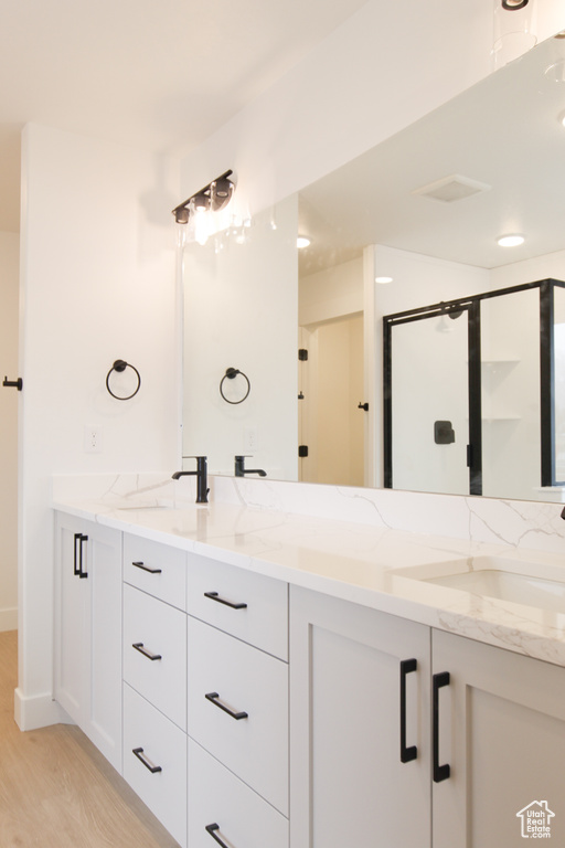 Full bath featuring wood finished floors, a sink, and double vanity