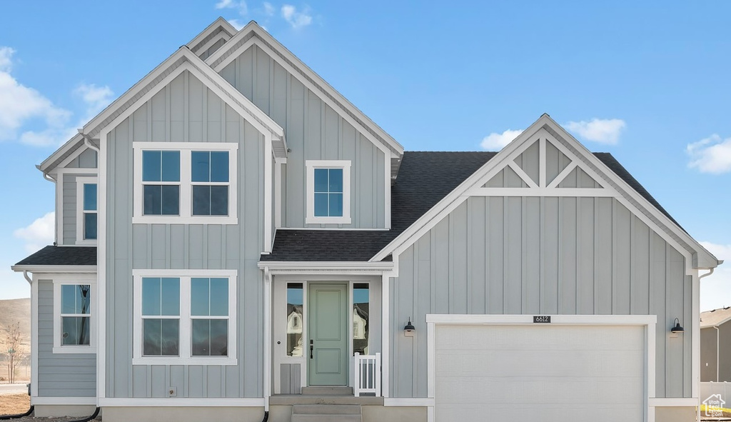 View of front of property featuring a shingled roof, board and batten siding, and an attached garage