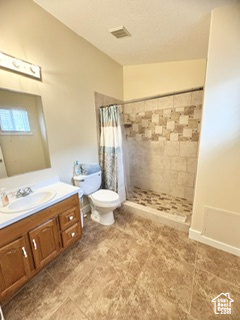 Full bathroom with visible vents, toilet, vaulted ceiling, vanity, and tiled shower
