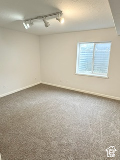 Spare room with carpet floors, baseboards, and a textured ceiling