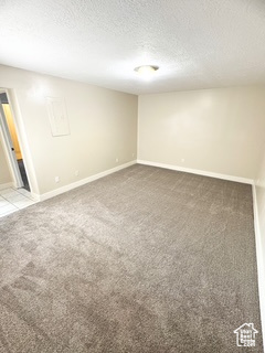 Carpeted spare room featuring a textured ceiling and baseboards
