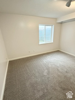 Carpeted spare room with ceiling fan and baseboards