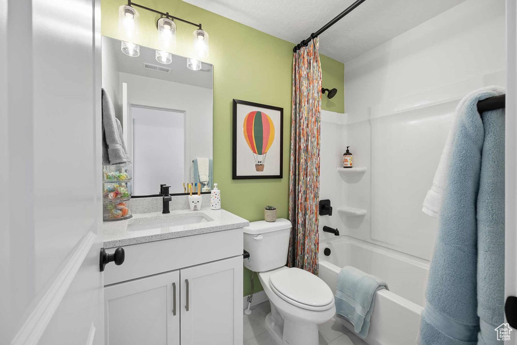 Bathroom featuring vanity, shower / bath combo, tile patterned floors, and a textured ceiling