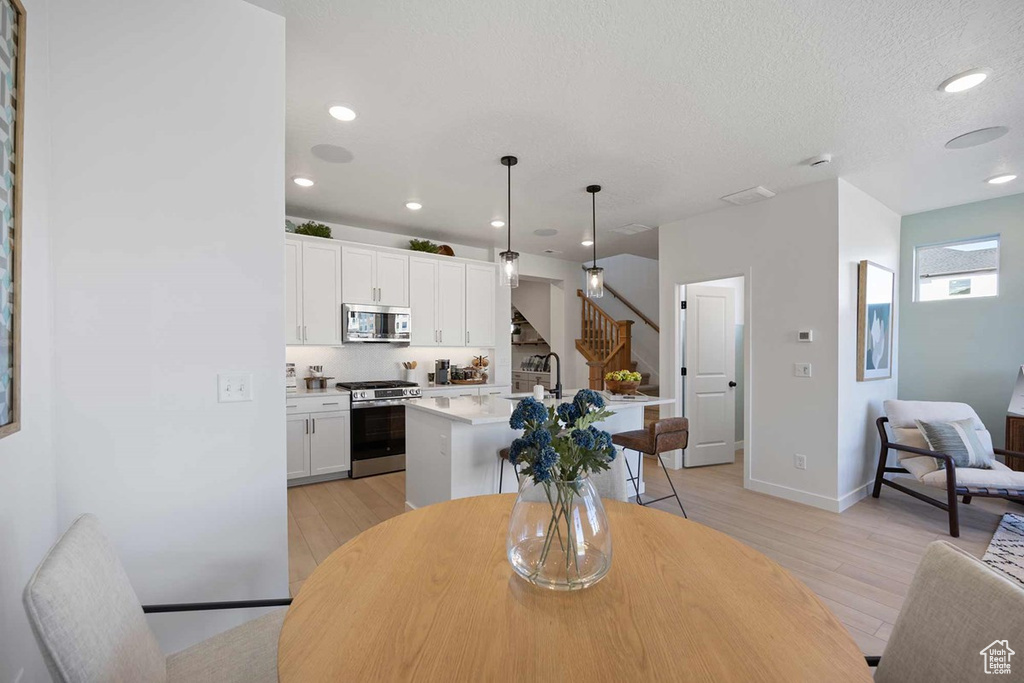 Dining space featuring stairs, light wood finished floors, and recessed lighting