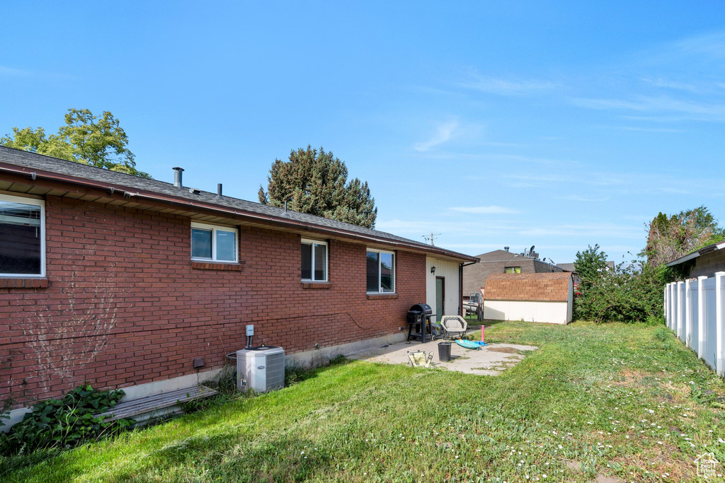 Back of house with central AC, brick siding, a patio, and an outdoor structure