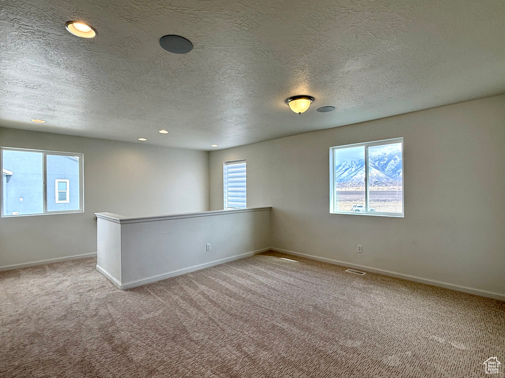 Carpeted empty room with recessed lighting, visible vents, a textured ceiling, and baseboards