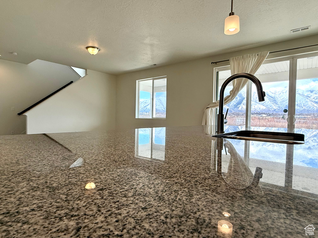 Interior details with a textured ceiling, stone countertops, and visible vents