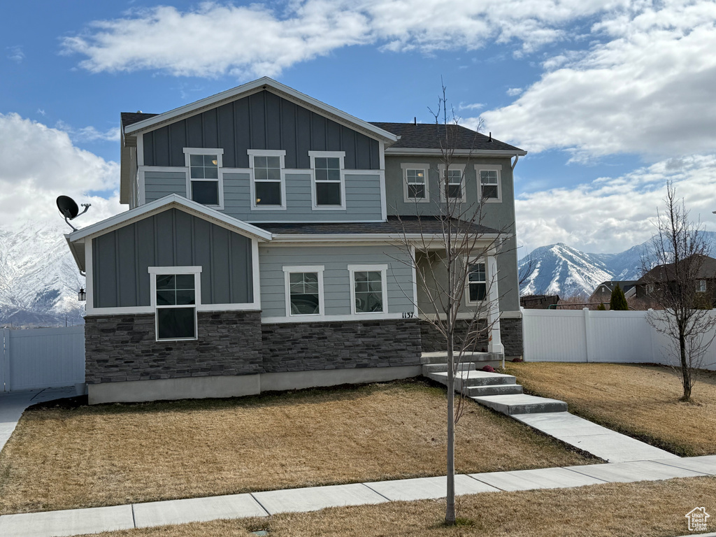 View of front of home featuring board and batten siding, stone siding, and fence