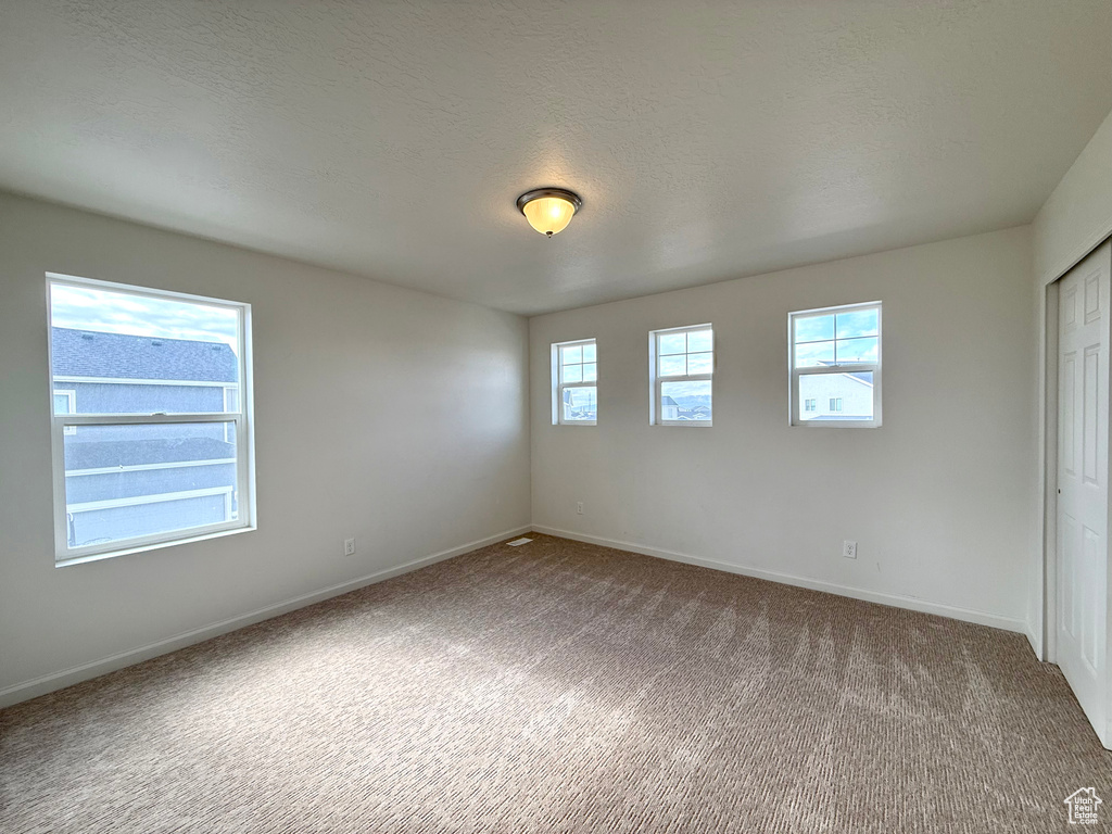 Unfurnished bedroom with a textured ceiling, carpet floors, a closet, and baseboards